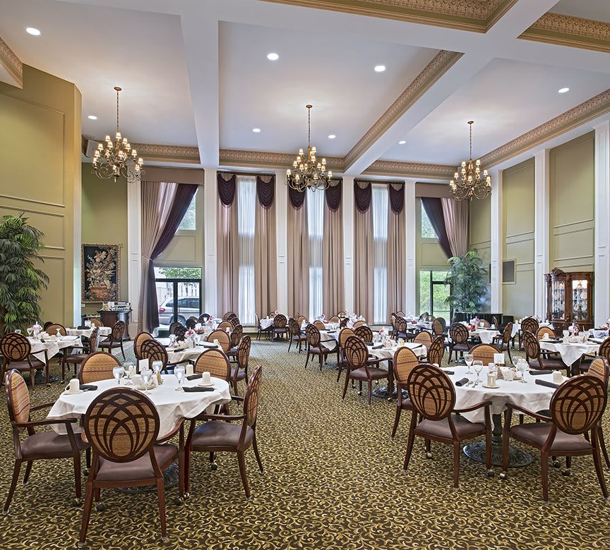 An elegant dining room with chandeliers and neatly arranged tables and chairs.
