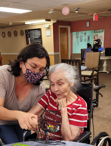 A caregiver attentively assists an elderly woman in a warm and supportive environment.