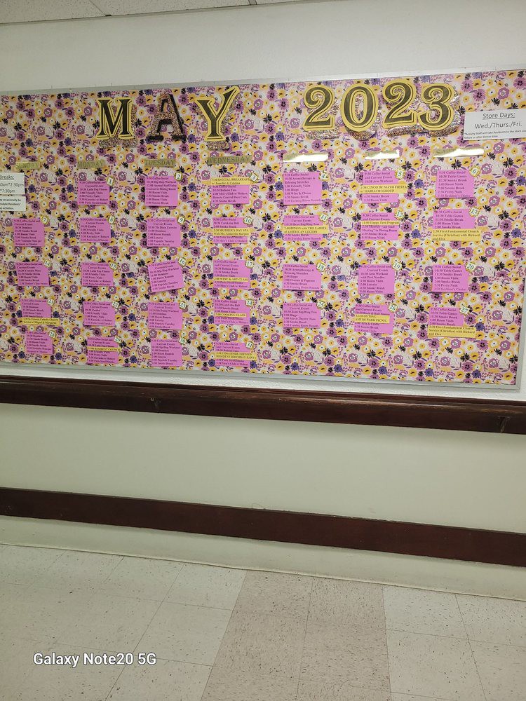 A colorful bulletin board displays a May 2023 theme with pink papers arranged in a calendar format.