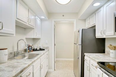 A modern kitchen with white cabinets and stainless steel appliances.