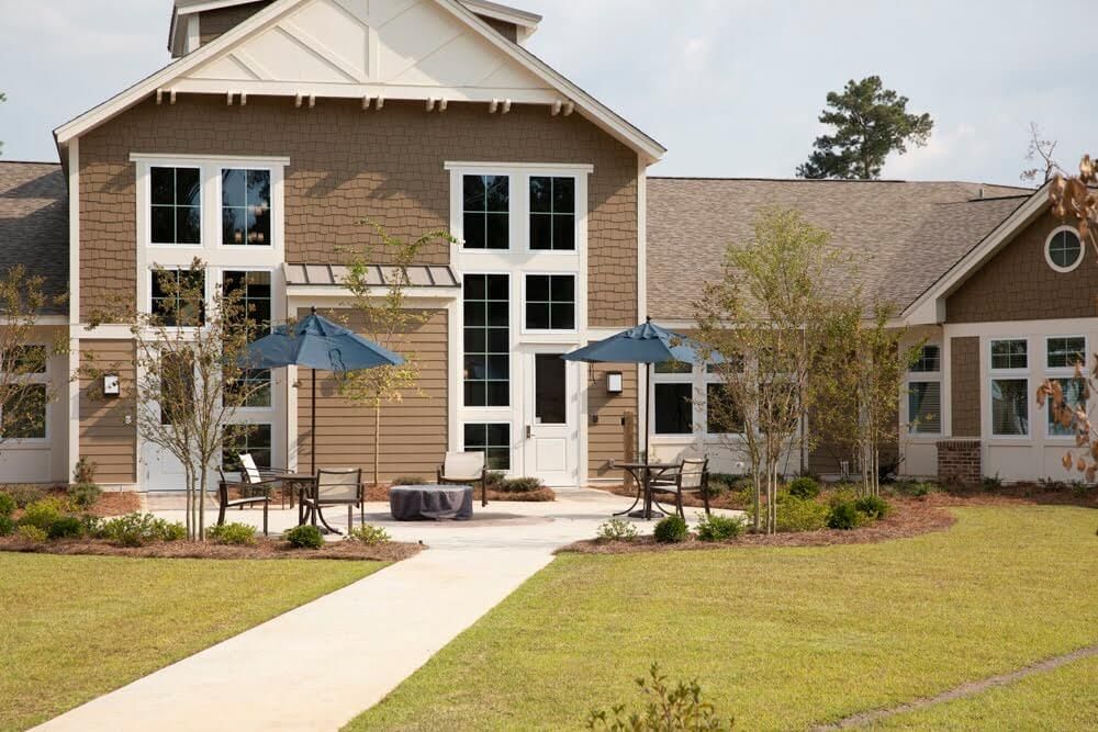 A residential building with a patio area featuring blue umbrellas and landscaping.