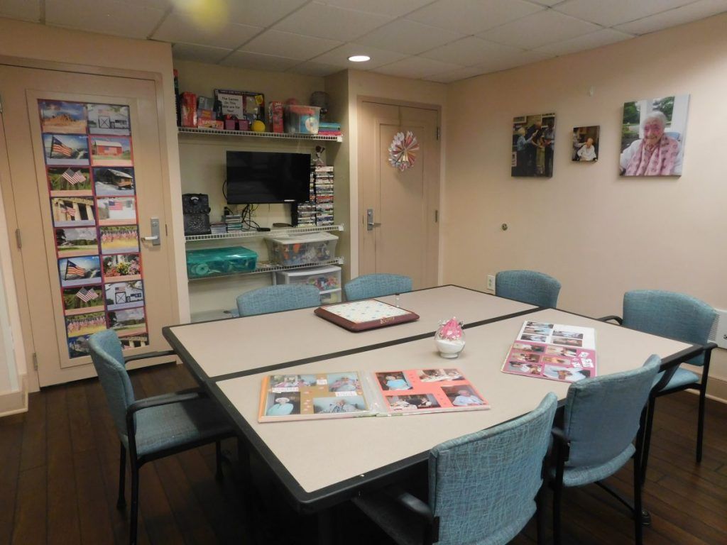 A meeting room with a large conference table surrounded by chairs, featuring magazines on the tabletop and decorative elements on the walls.