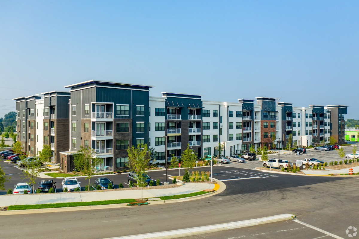 A modern apartment complex with landscaped areas and parking facilities.
