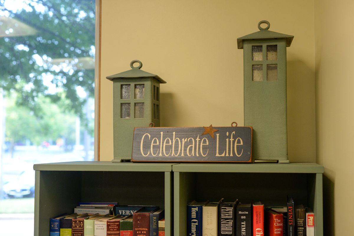 A cozy bookshelf decorated with lanterns and a sign reading 'Celebrate Life'.