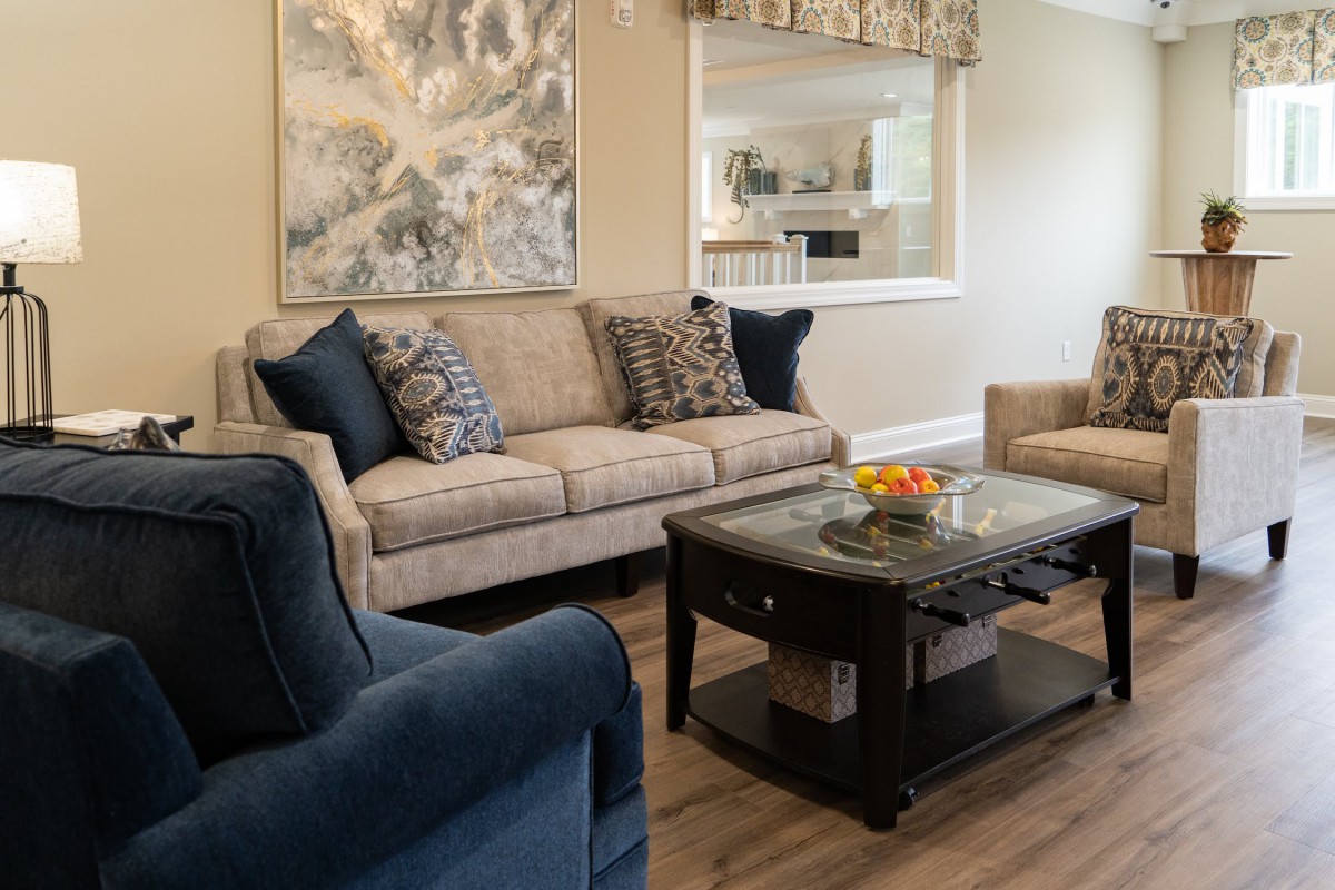 A cozy living room with a beige sofa, blue armchair, wooden coffee table, and decorative cushions.