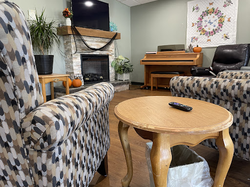 A cozy living room setting featuring patterned chairs, a wooden table, and a fireplace.