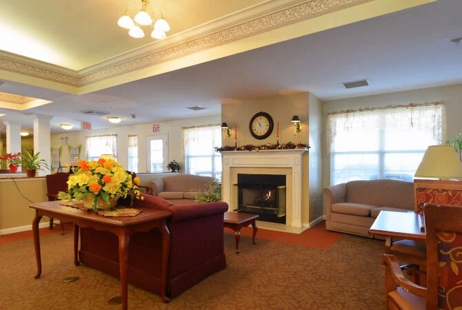 A cozy living room with sofas, a fireplace, and floral decor.