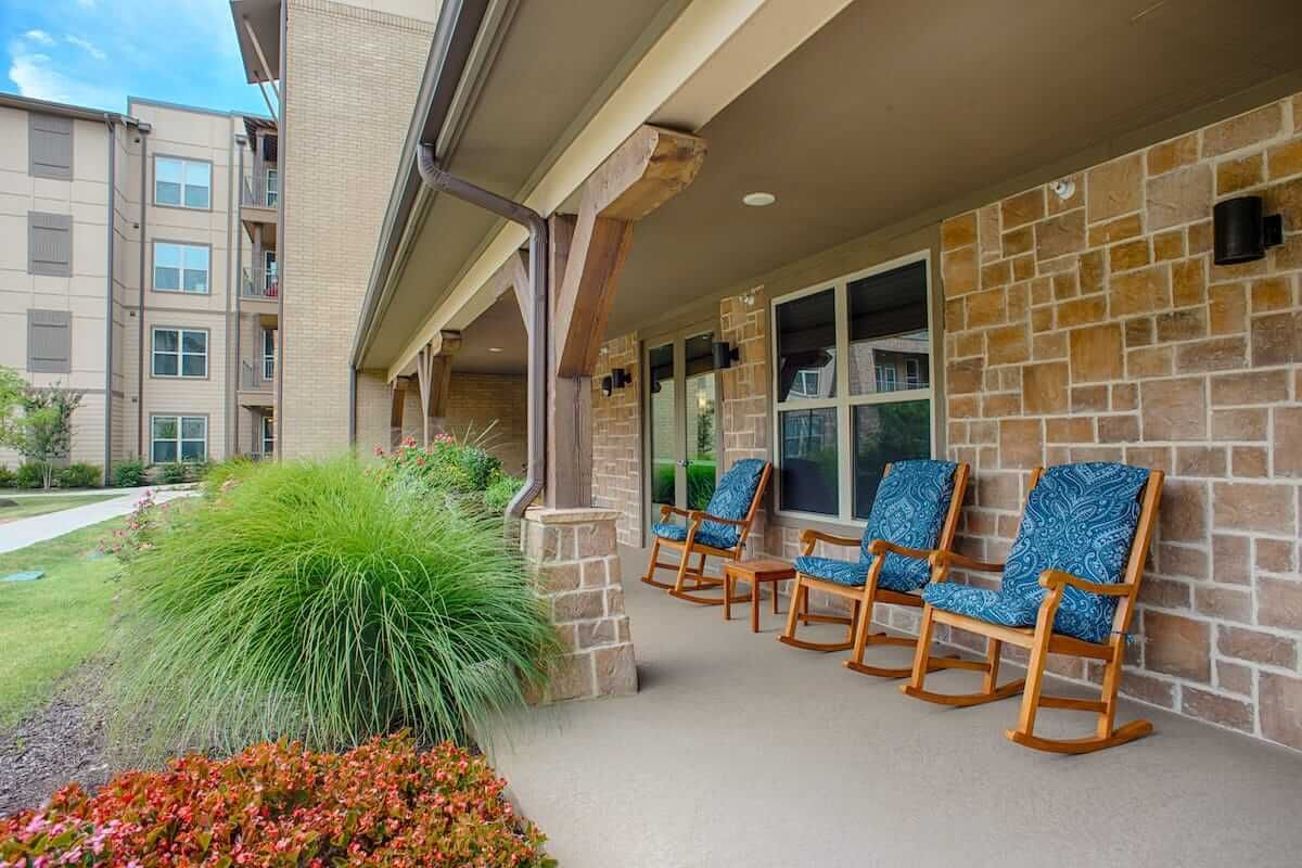A cozy porch featuring rocking chairs and lush greenery.