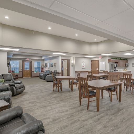 A spacious lounge area featuring multiple tables, chairs, and comfortable seating with modern lighting.