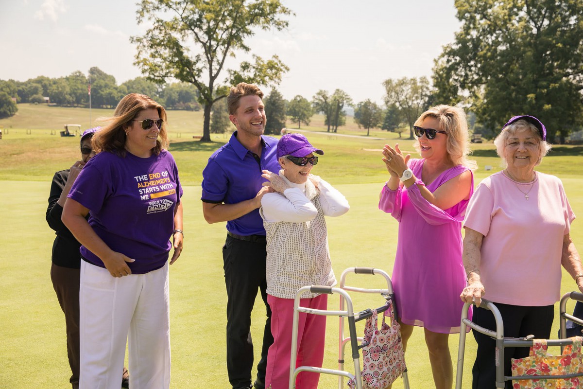 A group of people celebrating outdoors on a golf course during the day.