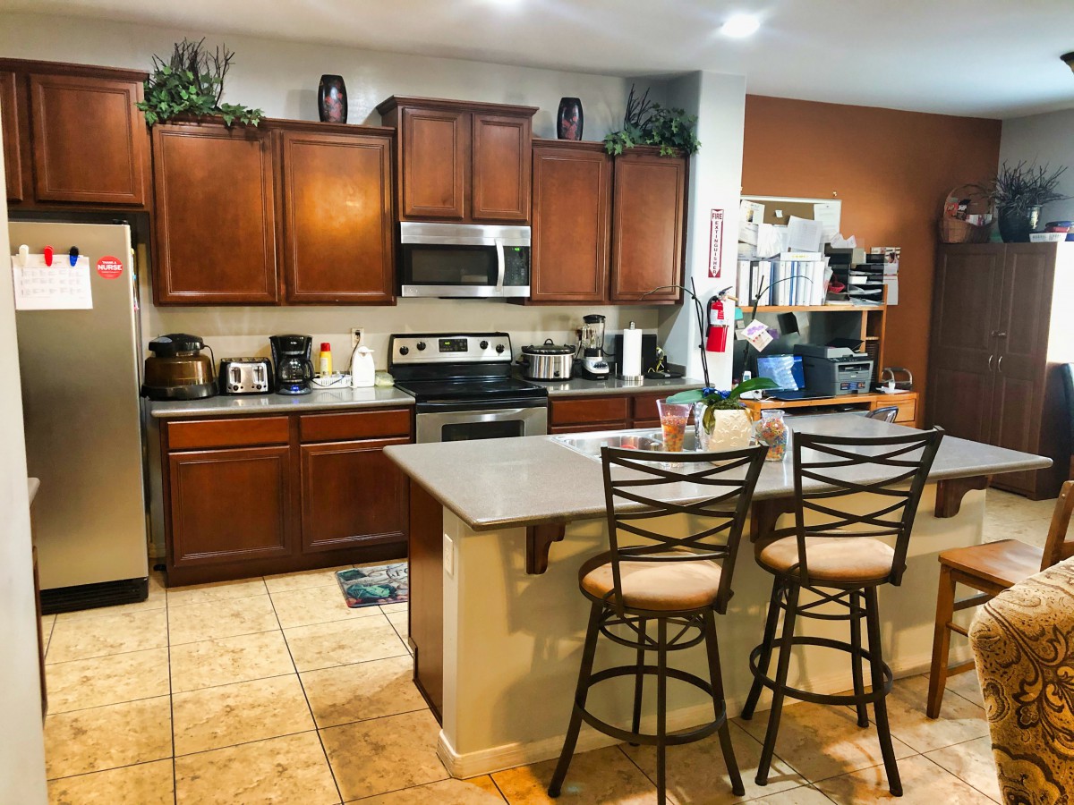 A modern kitchen with wooden cabinets, a central island, and bar stools.