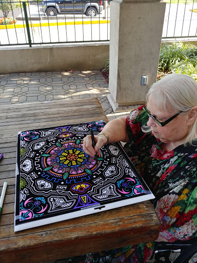 A woman colors a detailed mandala design outdoors, showcasing her artistic creativity.