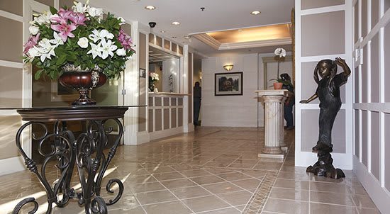 Elegant hotel lobby with a reception desk and floral arrangement.