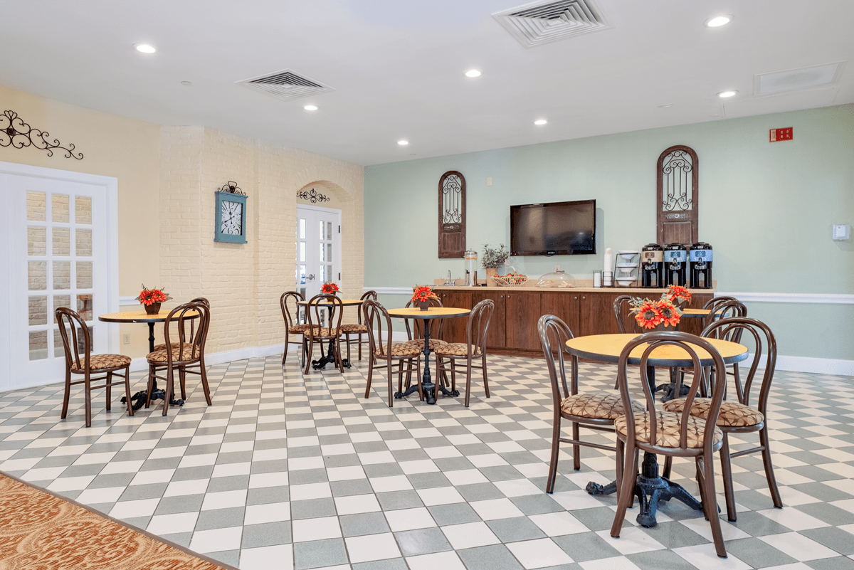 A cozy indoor cafe with checkered flooring and neatly arranged tables and chairs.