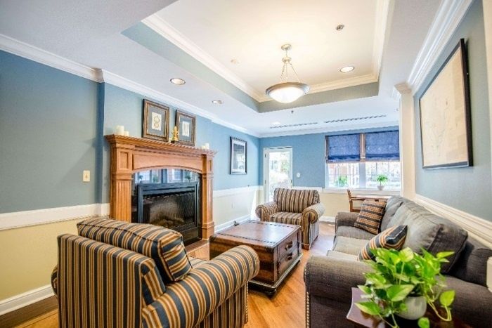A cozy living room with a fireplace, striped furniture, and blue walls.