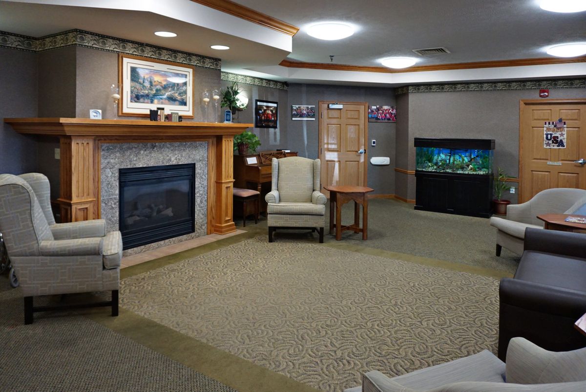 A cozy living room featuring a fireplace, an armchair, and an aquarium.