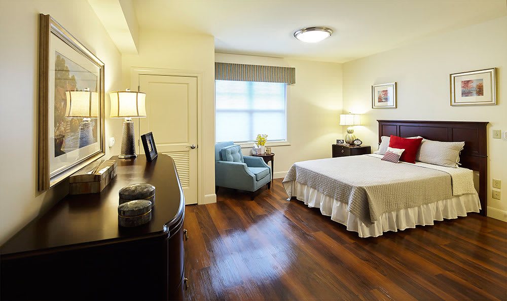 A cozy and well-lit bedroom featuring a large bed with crisp linens, wooden floors, and stylish decor.