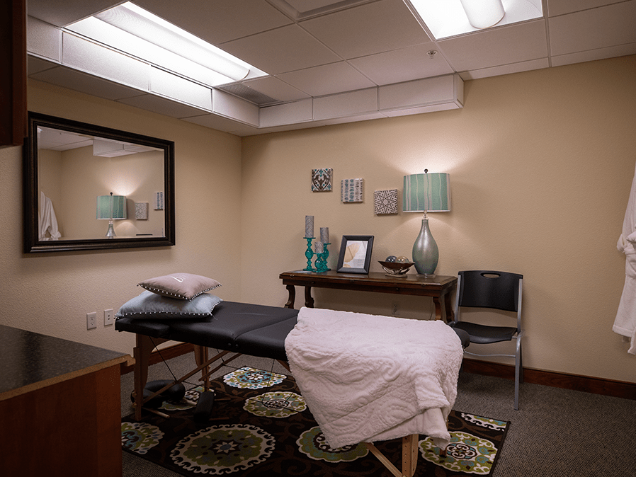 A cozy massage therapy room with a treatment table and soothing decor.