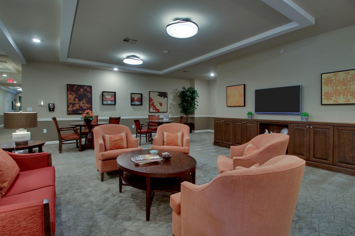 A cozy lounge area featuring comfortable armchairs, a round table, and decorative artwork on the walls.