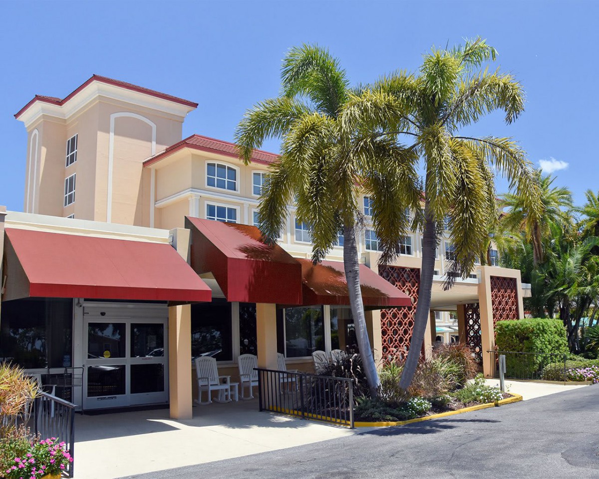 A sunny day at a restaurant with outdoor seating and palm trees.