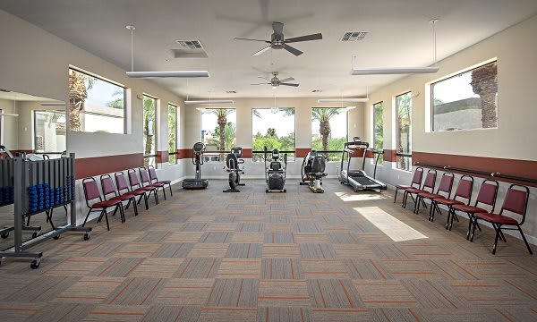 A well-lit fitness room with exercise equipment and seating.