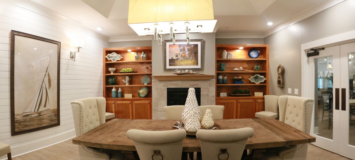 A modern dining room with elegant decor, featuring built-in wooden shelves, a central fireplace, and contemporary lighting.
