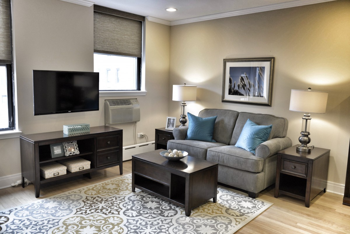 A cozy living room with a sofa, coffee table, and TV, featuring elegant decor and warm lighting.