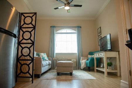 A cozy living room with modern decor, featuring a sofa, television, and a window with curtains.