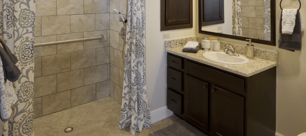 A modern bathroom with a tiled shower area, dark cabinets, and a decorative curtain.