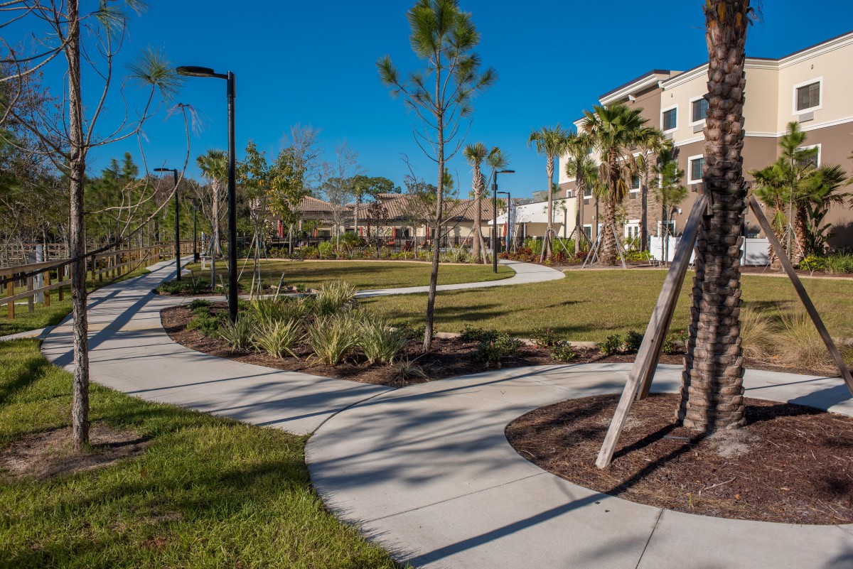 A scenic view of a park walkway surrounded by greenery and buildings.