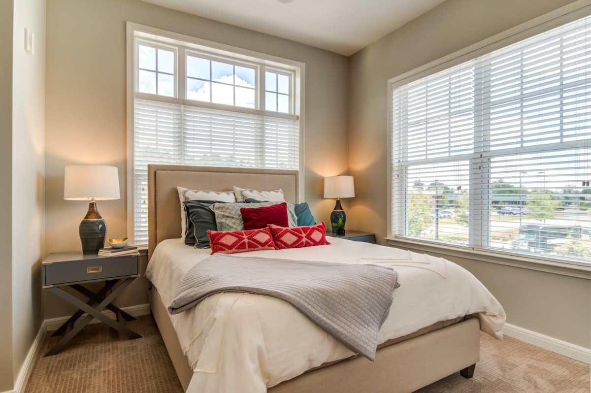 A cozy and modern bedroom with ample natural light coming through two large windows.