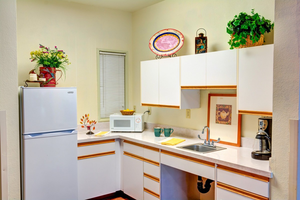 A bright kitchen interior with white cabinets, a refrigerator, and a microwave.
