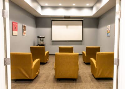 A cozy home theater setup with yellow armchairs and a projector screen.