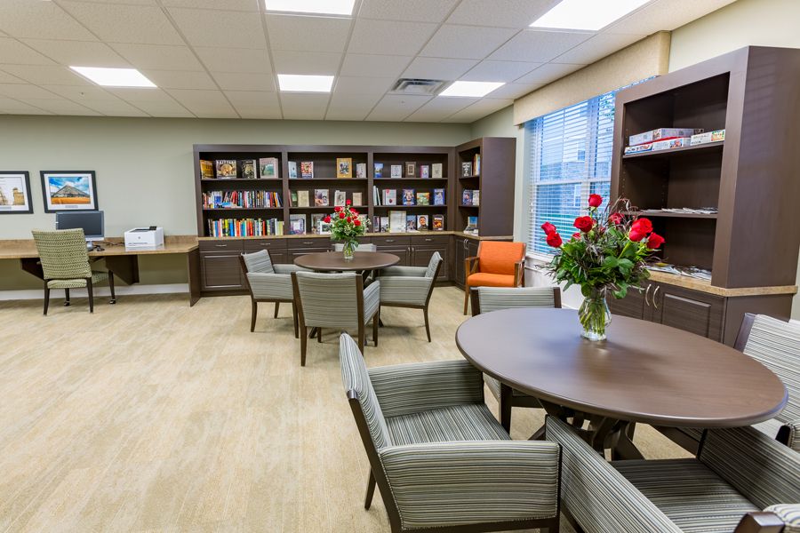 A cozy library space with shelves of books, tables, and chairs for reading.