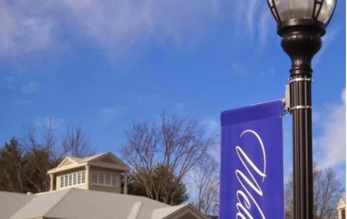 An outdoor sign stands in front of a building with a clear blue sky in the background.