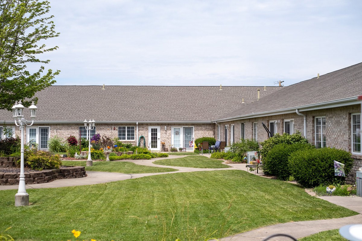 A landscaped courtyard with a well-kept lawn in front of a long, single-story building.
