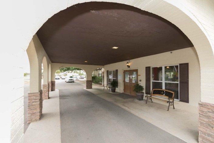 A covered driveway entrance to a building with outdoor seating.