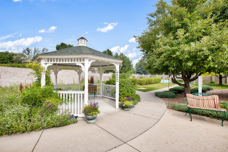 A serene garden scene with a white gazebo and winding pathway.