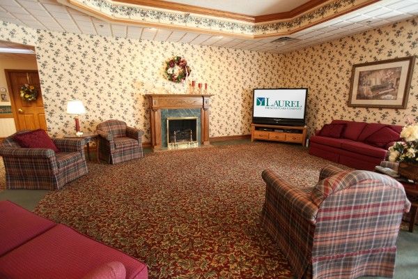 A cozy living room with floral wallpaper, featuring a fireplace, television, and comfortable seating.