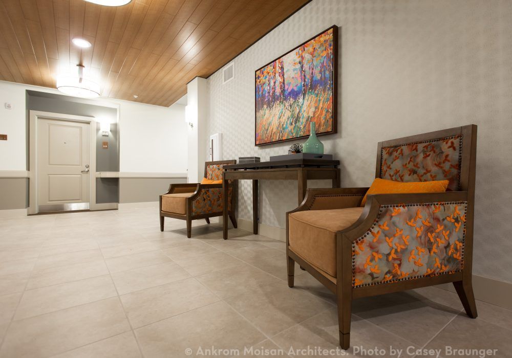 A modern lounge area featuring two armchairs, a console table, and colorful wall art.