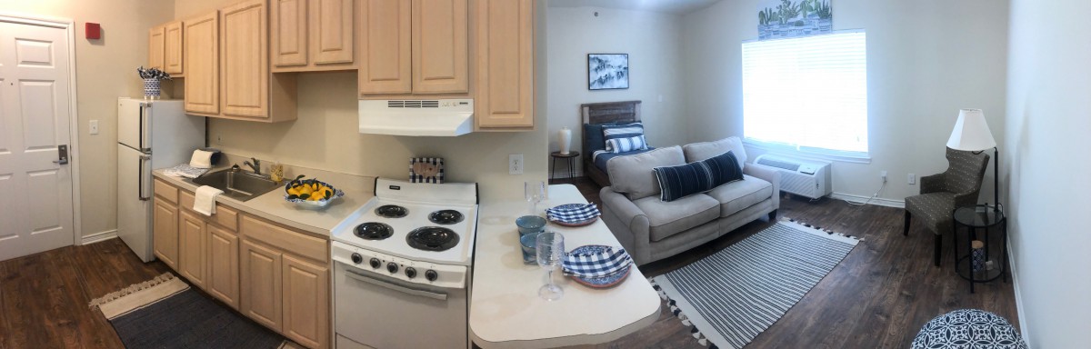 A cozy apartment interior featuring a compact kitchen with an oven and a small living area with a couch and modern decor.