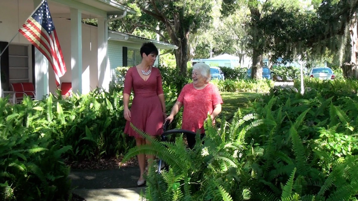 Two women walking and talking in a garden setting during the day.
