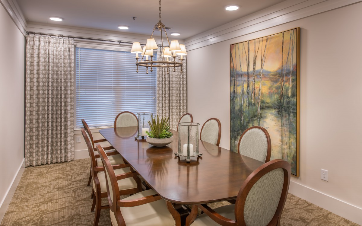 A beautifully designed dining room featuring a large wooden table, elegant chairs, a stylish chandelier, and wall artwork.