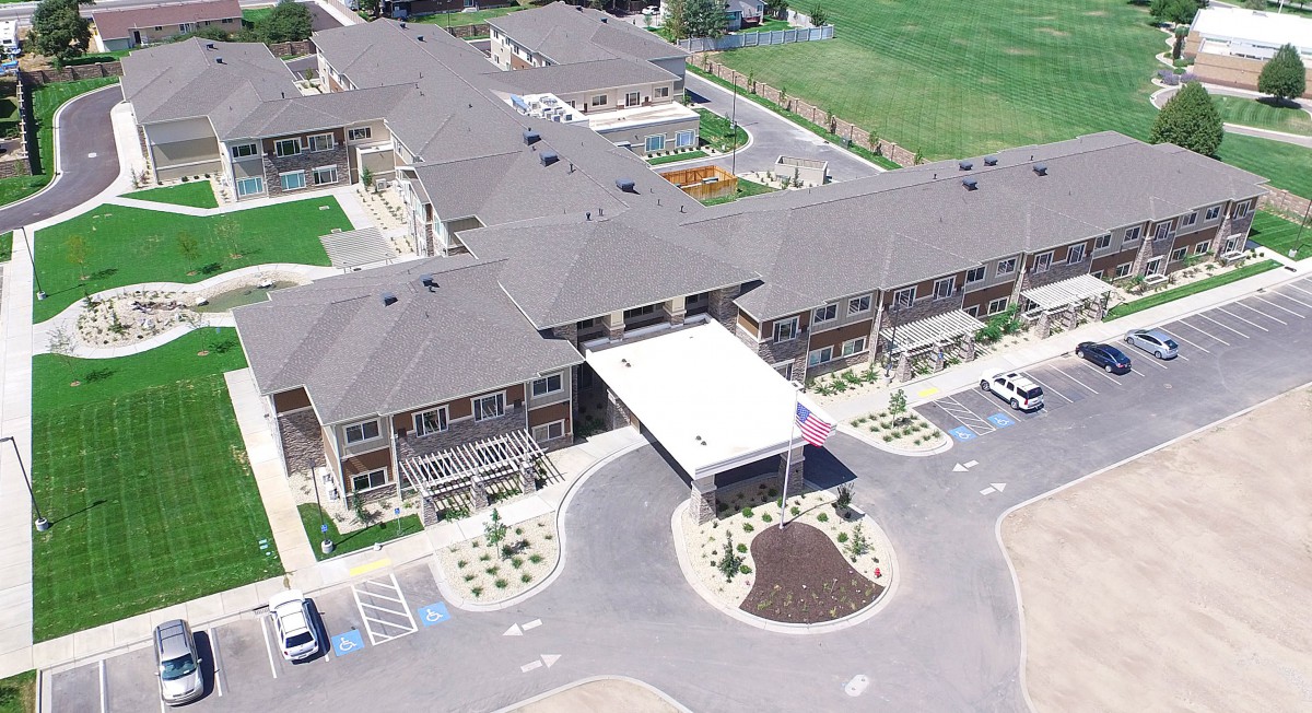 Aerial view of a large building complex with landscaped surroundings and parking areas.