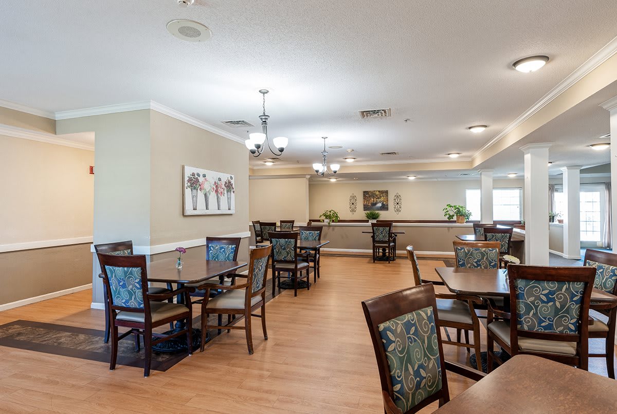 A spacious dining area with tables and chairs, decorated with artwork and lighting fixtures.
