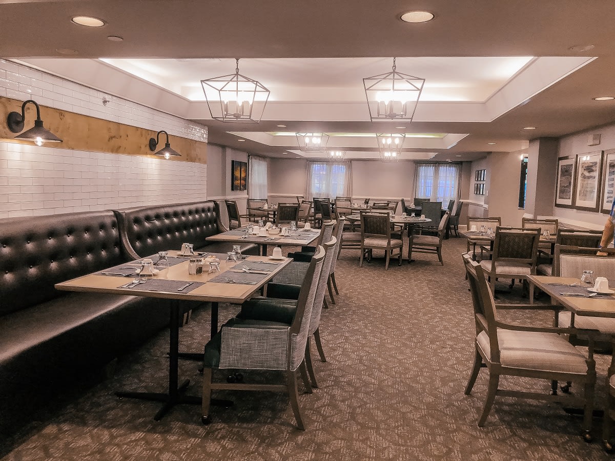 An empty restaurant dining area with neatly arranged tables and chairs.