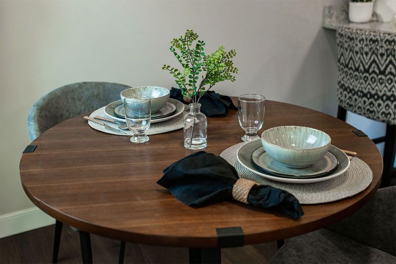 A modern dining table setup with ceramic bowls, elegant place settings, and a touch of greenery.