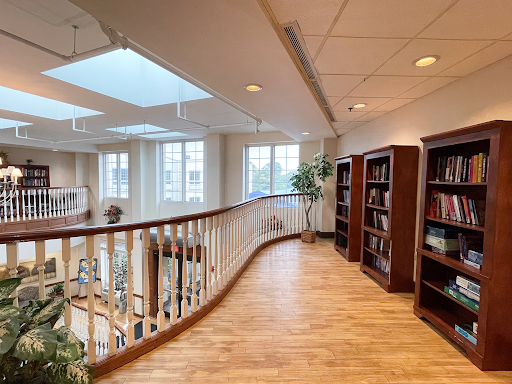 A spacious library interior featuring wooden bookshelves and abundant natural light from skylights.
