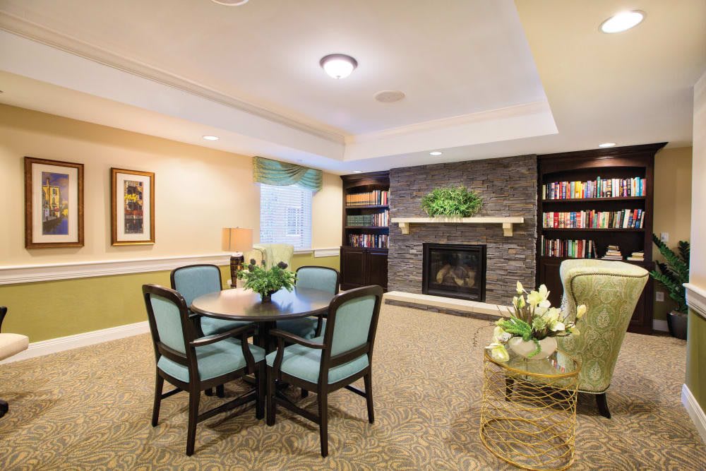 A cozy living room with a fireplace, bookshelves, and a round table surrounded by chairs.