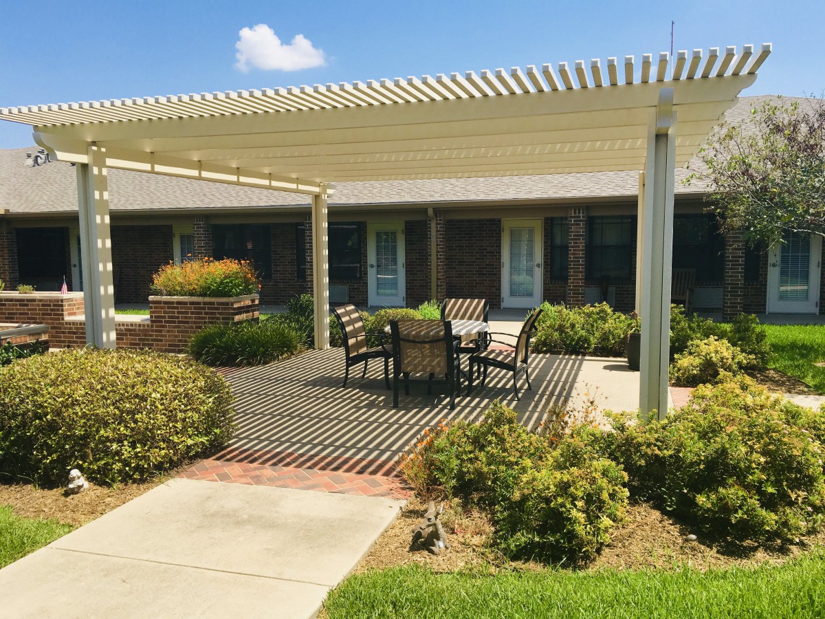 A cozy outdoor patio with a pergola and seating area surrounded by greenery.